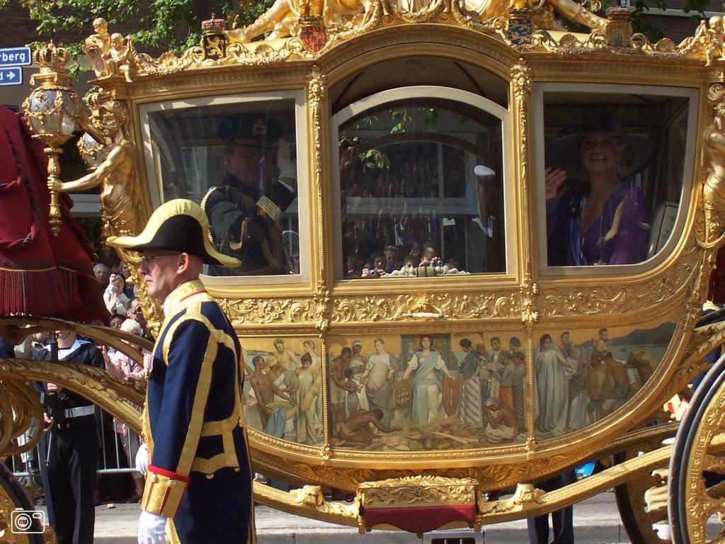 Le roi et la reine de Hollande dans un carrosse royal doré Remarquez en bas : les peuples des colonies, parmi lesquels des Africains, viennent se prosterner devant une femme blanche qui représente les Pays Bas. L'offense ici n'a pas de limite. Les Pays Bas se sont enrichis grâce aux produits de leurs colonies esclavagistes. 